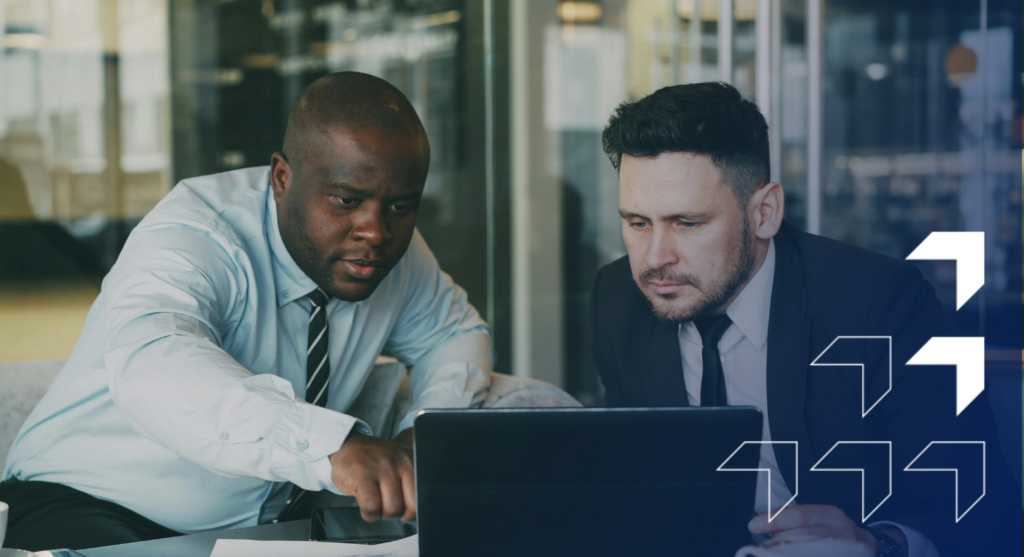 Two business professionals reviewing data on a laptop in a modern office setting.