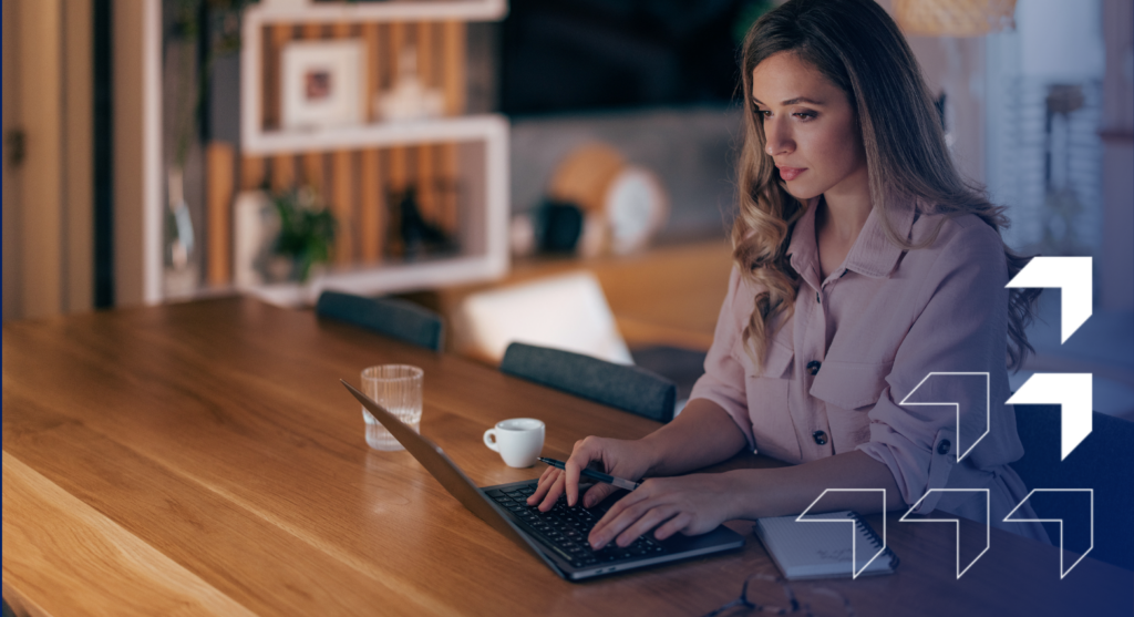 Woman in business attire working on laptop at wooden desk with coffee cup in modern office environment